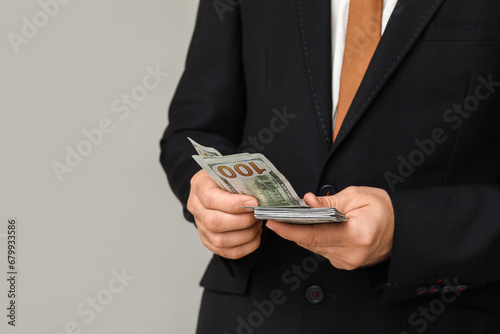 Young businessman with bribe on light background, closeup