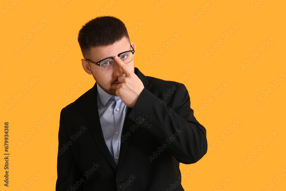 Young thoughtful businessman on yellow background. Business idea concept Young thoughtful businessman on yellow background. Business idea concept