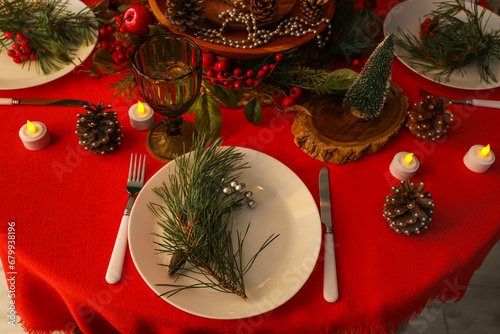 Christmas table setting with fir branches in room at night, closeup