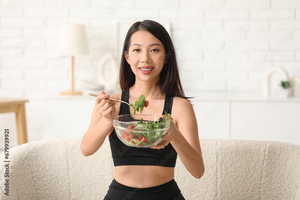 Beautiful young Asian woman with bowl of fresh vegetable salad at home. Weight loss concept