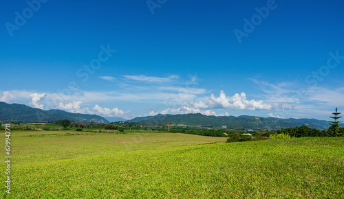 Green grass field and mountain view with blue sky. Nature background. Countryside landscape