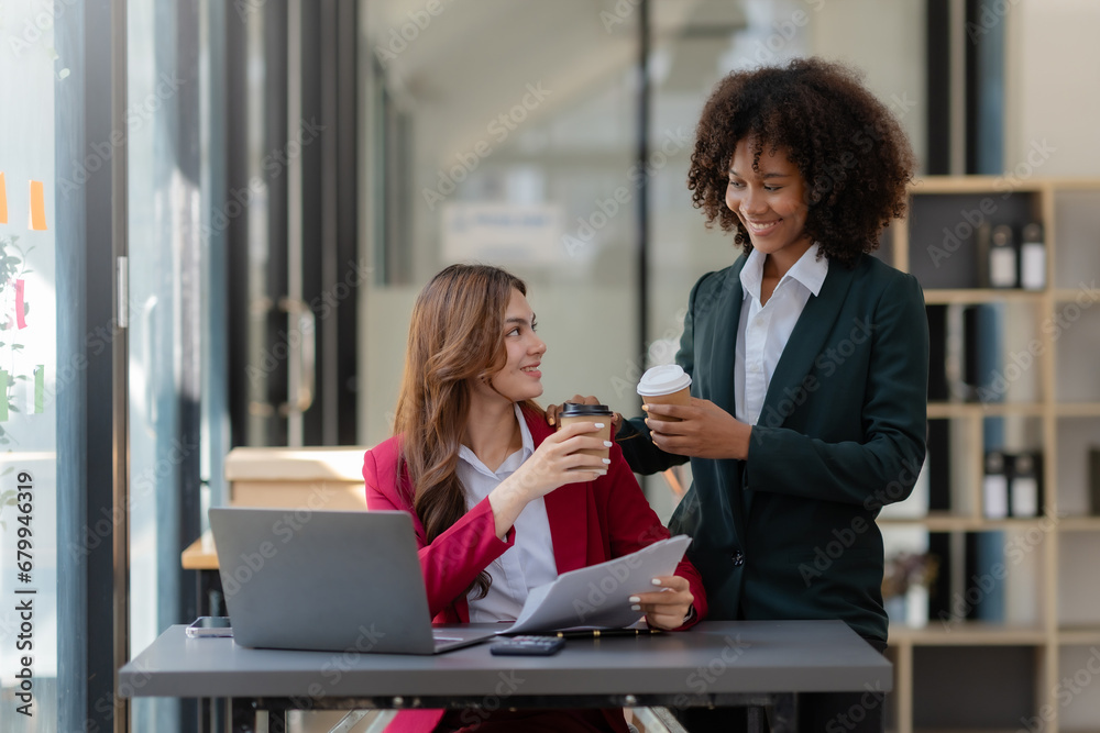 Two business woman using laptop talking and consulting working together in the office. Two business colleagues having a discussion during a meeting. Two business woman using laptop talking and consulting working together in the office. Two business colleagues having a discussion during a meeting.