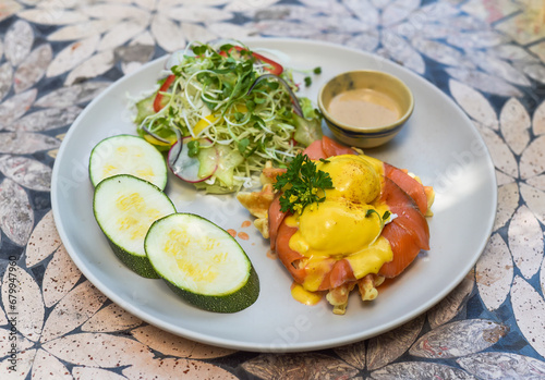 white plate with eggs bennedict waffles with smoked salmon on a white background