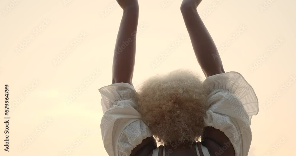 Rear View of a young African American woman in a white dress with curly ...