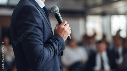 Motivational speaker with headset performing on stage with microphone in haand, back view