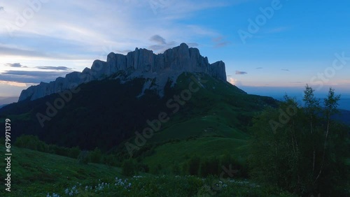 Beautiful view of high rocks sticking out against the blue sunset sky. In the foreground evening swaying tree branches. Summer hike in the mountains. Sunset in the mountains photo