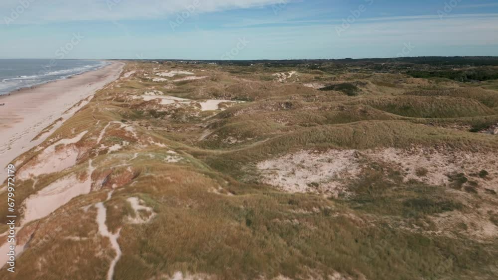 Expansive dunes along the Danish coastline under blue skies. Expansive dunes along the Danish coastline under blue skies.