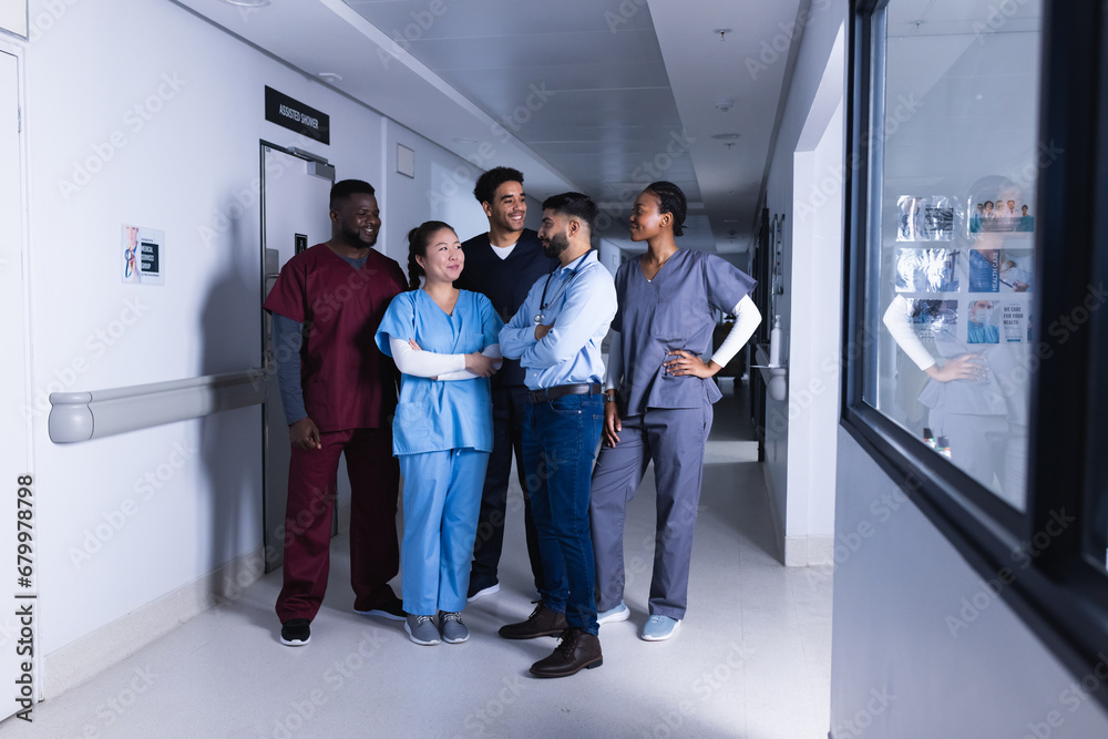 Fototapeta premium Happy diverse male and female doctors talking in hospital corridor
