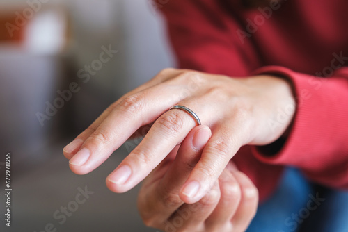 Closeup image of a woman putting on a silver ring on her ring finger