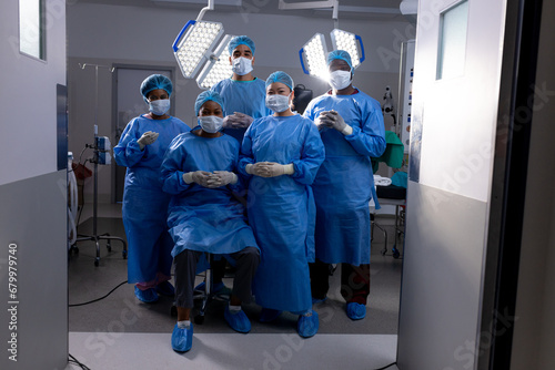 Portrait of diverse male and female doctors wearing face masks in hospital operating room photo