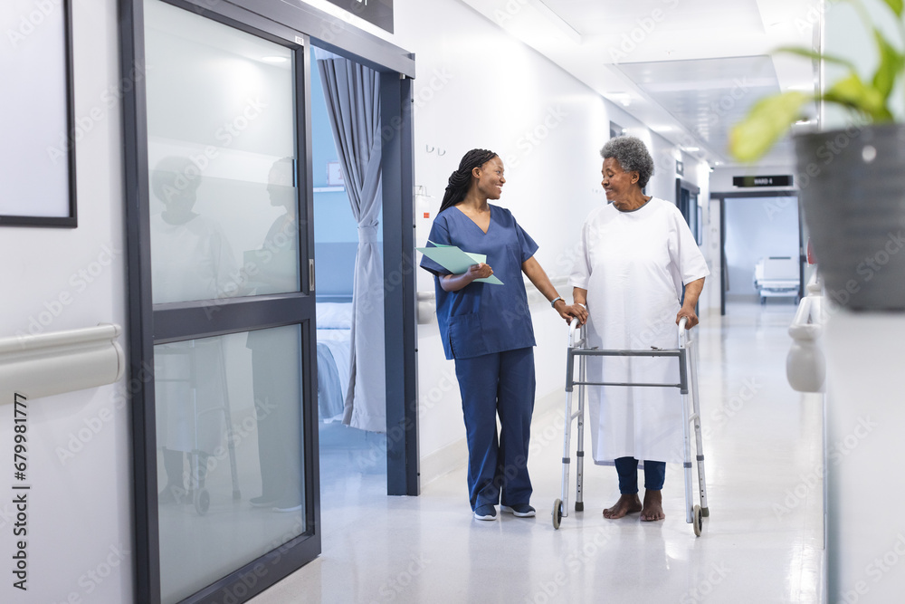 African american female doctor talking with senior female patient with crutches in hospital corridor African american female doctor talking with senior female patient with crutches in hospital corridor