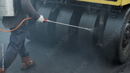 Water spraying on pneumatic tyred roller. Process asphalting road construction infrastructure by compressing, compacting, leveling and smoothing the asphalt road surface using a pneumatic tyred roller photo