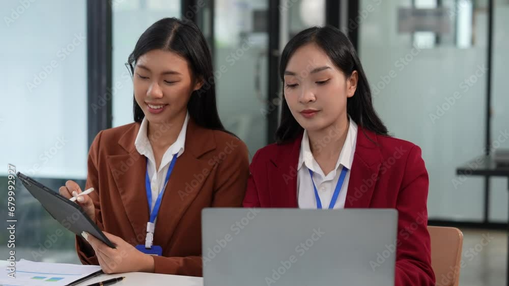 Two young Asian business women work on financial documents in the office, analyzing financial statistics with laptops. Plan the company's budget and accounting. Two young Asian business women work on financial documents in the office, analyzing financial statistics with laptops. Plan the company's budget and accounting.