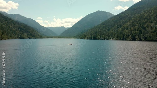 overview of a lake in the mountains and a sailing boat with a group of tourists