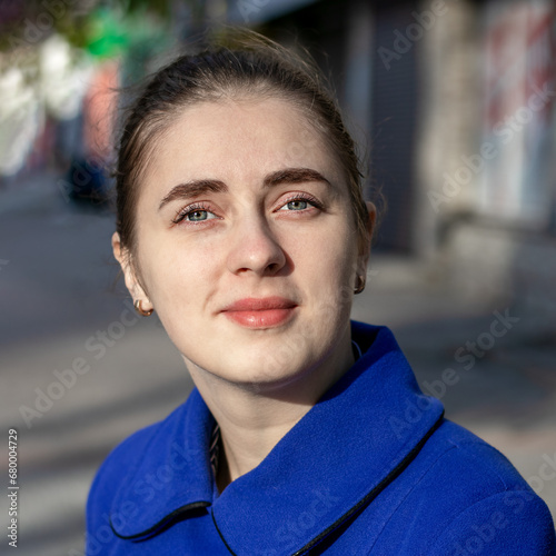 A young girl looks at the camera while walking on the street.