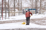 A person removes the first snow on the house territory. A large shovel removes the first white snow.