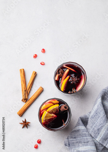 Mulled wine with orange, apple and cinnamon in glasses on a light background. The concept of a traditional winter hot drink with spices and fruits.