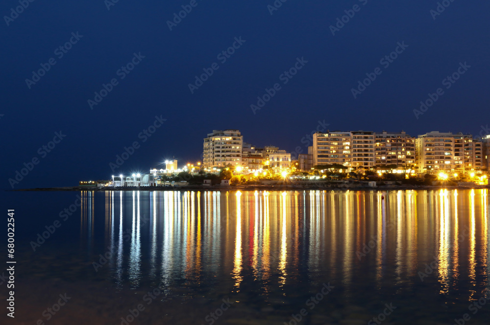 Long reflections of seaside resort night lights on calm water of Mediterranean sea bay. Long reflections of seaside resort night lights on calm water of Mediterranean sea bay.