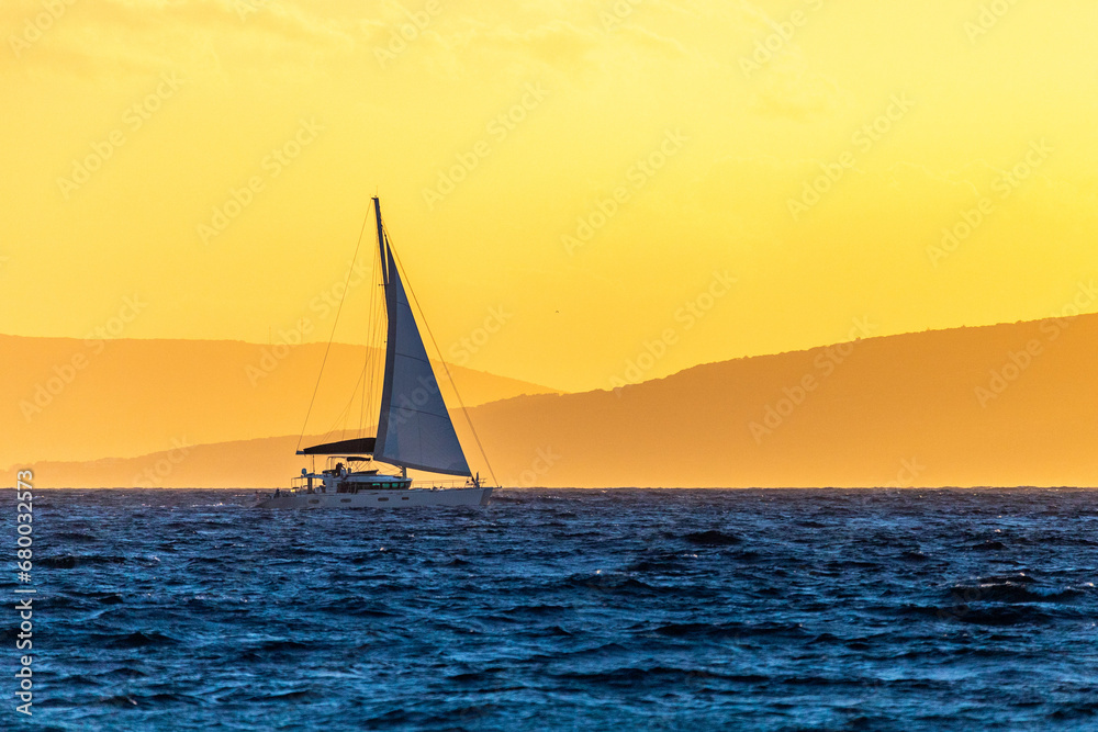 Yacht sailing in the sea during beautiful sunset with background of mountains fiiled with sunset light