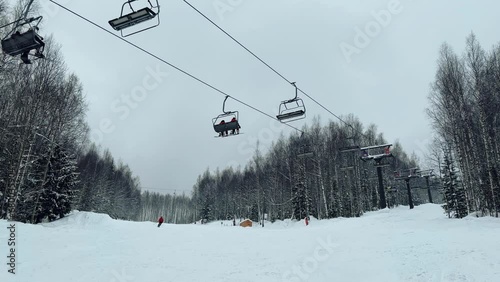 A chairlift at a ski resort on a cloudy winter day in the Ural Mountains. A lift on the background of factory pipes. Climbing the mountain. Gubakha, Perm Krai, 4K photo