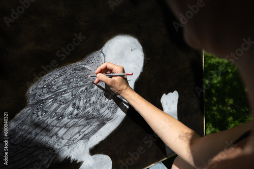 Adult Caucasian Woman Drawing a Snow Owl with a Pencil on a Dark Background - Real Artist, Real Artwork on Paper Made for a series of forest Wildlife photo