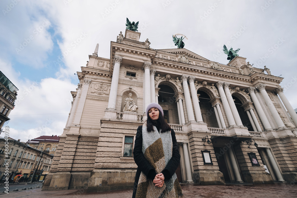 A young girl against the backdrop of the facade of the Lviv Opera and Ballet Theater. The central sculpture on the roof is 