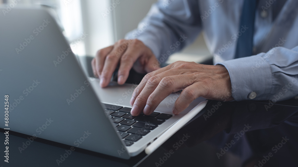 Businessman working on laptop computer at modern office. Business man hands typing on laptop computer keyboard, searching business data, surfing the internet Businessman working on laptop computer at modern office. Business man hands typing on laptop computer keyboard, searching business data, surfing the internet