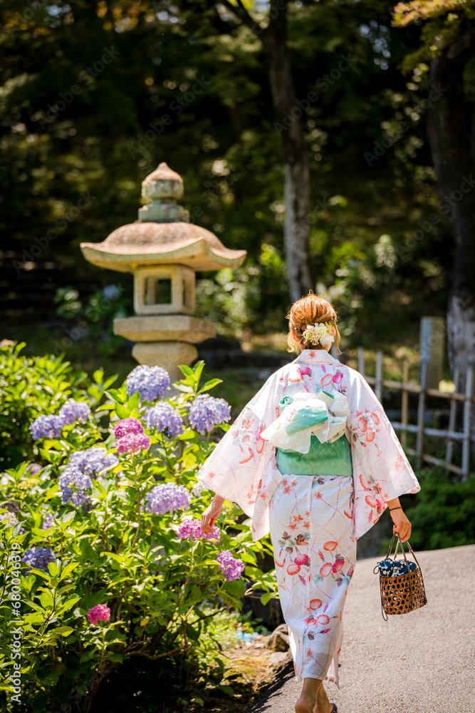 Portrait of a young woman wearing a Japanese yukata summer kimono in a hydrangea garden. Kyoto, Japan. soft blur background. Portrait of a young woman wearing a Japanese yukata summer kimono in a hydrangea garden. Kyoto, Japan. soft blur background.