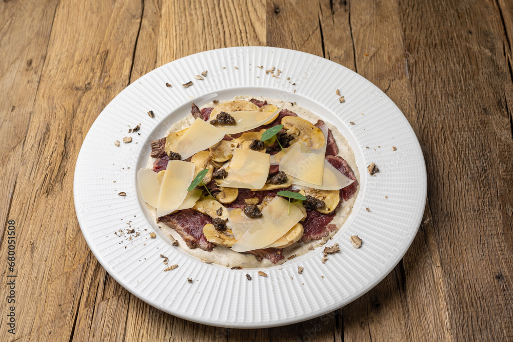Veal carpaccio with Parmesan on a wooden table Veal carpaccio with Parmesan on a wooden table