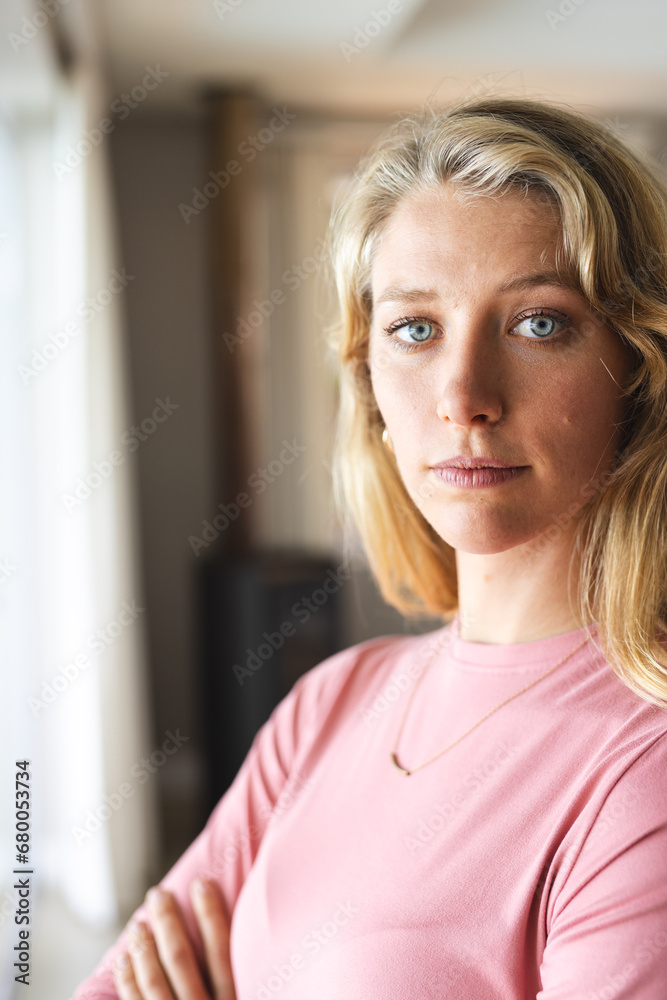 Thoughtful blonde caucasian woman looking at camera in sunny living room at home Thoughtful blonde caucasian woman looking at camera in sunny living room at home