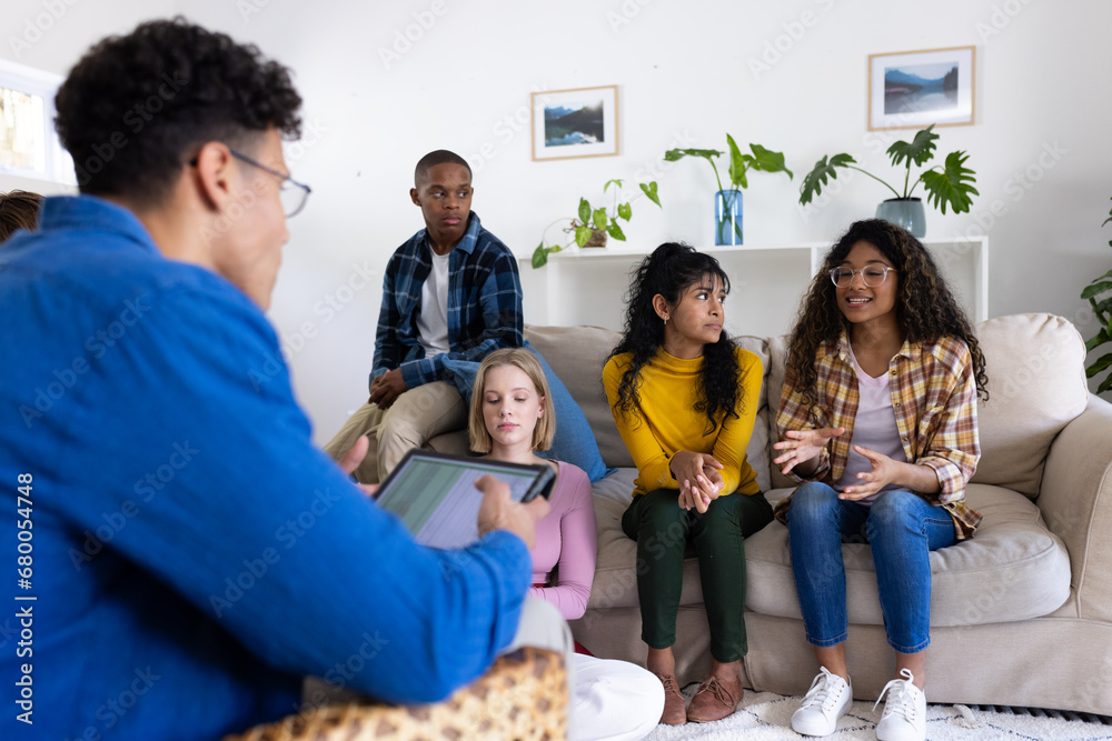 Thoughtful diverse group of teenage friends using tablet during therapy at home Thoughtful diverse group of teenage friends using tablet during therapy at home