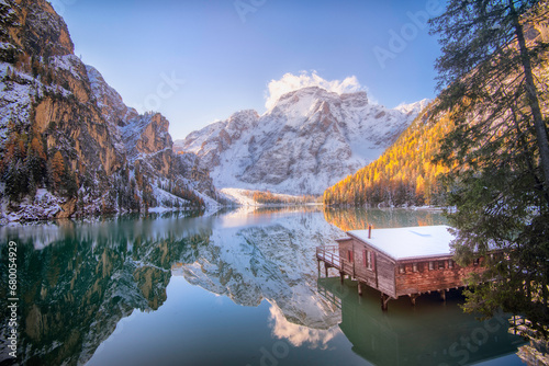 Fototapeta Naklejka Na Ścianę i Meble -  Le lago di Braies (lac de Braies) dans les Dolomites en Italie en hiver avec le reflet de la montagne dans le lac et le célèbre chalet et son ponton qui permettent l'acces aux barques de loisirs.