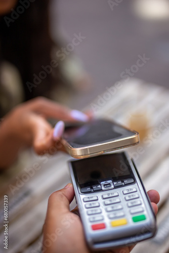 young woman with NFC technology in contactless payment terminal using her smartphone