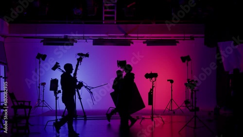 Professional filming pavilion with a neon cyclorama. The process of preparing for the shooting of a music video. Director, Cameraman and crew in Backstage.