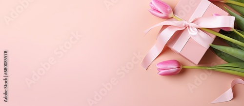 Mother s Day concept Top view photo of a pink giftbox with a ribbon and bouquet of tulips on a pastel pink background with space for text Copy space image Place for adding text or design
