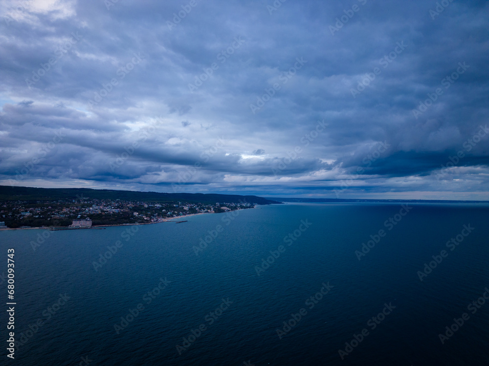 A bird's-eye view of a dark sea, horizon, and dramatic sky before a storm in the evening