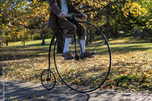 Man riding penny farthing bicycle in park. High wheeler bicycle ride