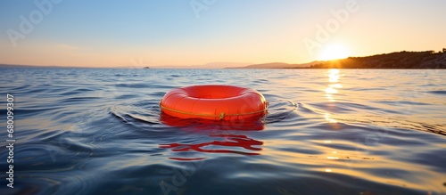 Orange lifebuoy floating in the sea at sunset. Summer vacation concept photo