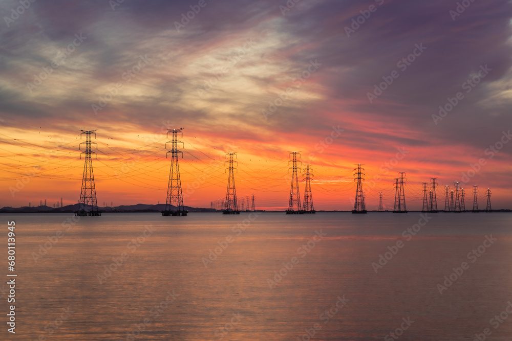 High-voltage transmission tower and sunset over the sea
