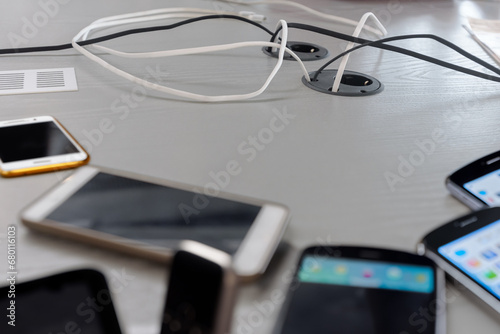 Fototapeta Naklejka Na Ścianę i Meble -  Smartphones charging at public place with electric plug and usb cable, Convenient public phone charging station, where smartphones get powered up for free.