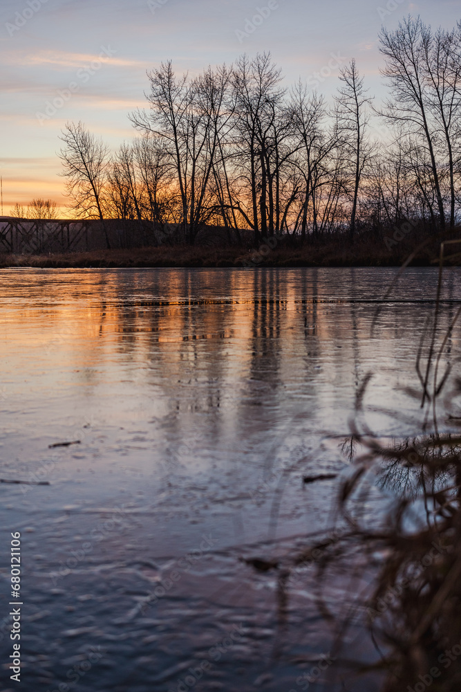 Frozen pond at sunset with trees in background
