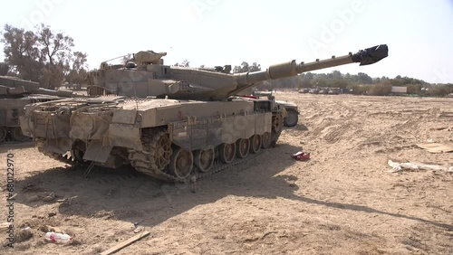 A handheld clip of an Israeli Merkava tank, waiting for action on the desert soil, some dust is lifted by light wind. Be'eri, Israel.