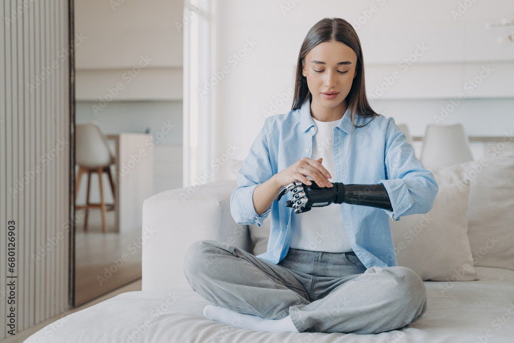 Obraz premium Serene young woman in meditation with a bionic arm, blending tranquility with technology in a modern setting