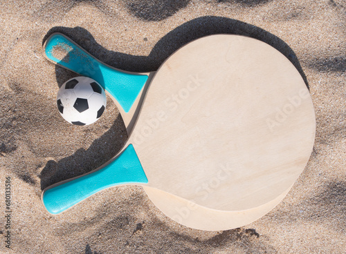 Beach ball rackets and a ball on a beach sand