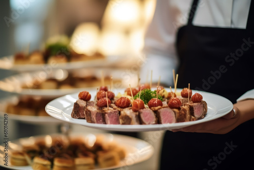Close up of woman waiter carrying plates with meat dish on some festive event in background of modern cafe. Event concept of food and dinner.