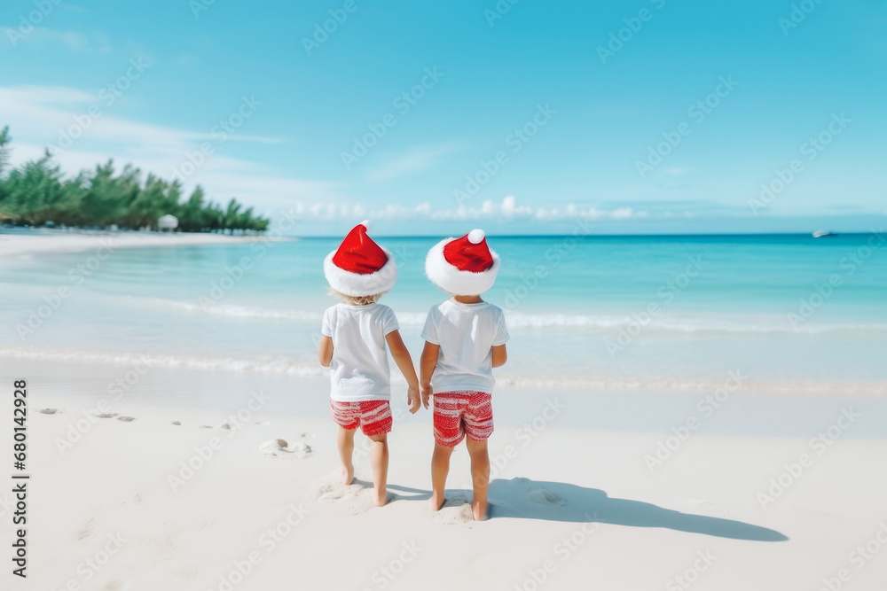 Two kids in Santa Claus hats on tropical beach with clear blue water. Christmas vacation concept. Two kids in Santa Claus hats on tropical beach with clear blue water. Christmas vacation concept.