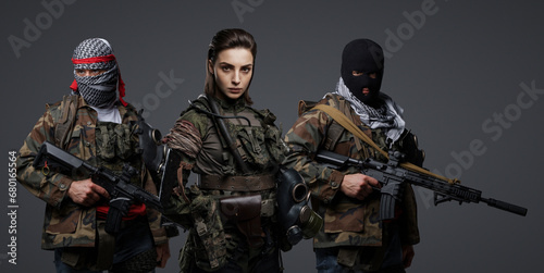 Group of three Middle Eastern militants dressed in camouflage uniforms, keffiyehs, and balaclavas posing against a gray background photo