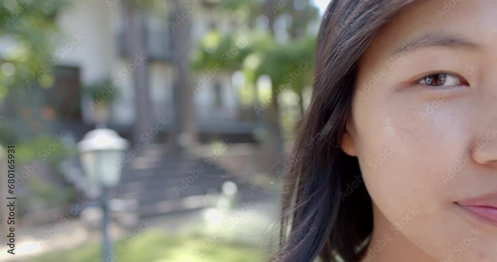 Half face of happy asian woman standing and smiling in sunny garden, slow motion, copy space Half face of happy asian woman standing and smiling in sunny garden, slow motion, copy space