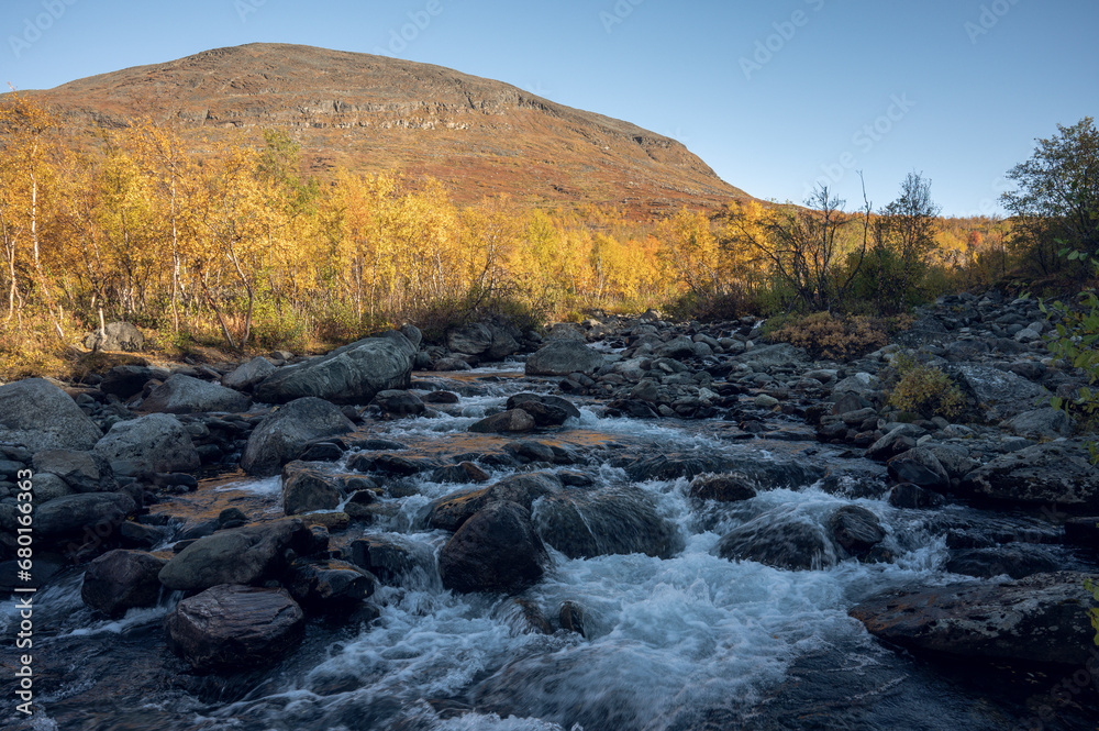 River flows in the vast landscape of Swedish Lapland on an autumn evening with surrounding autumn colors River flows in the vast landscape of Swedish Lapland on an autumn evening with surrounding autumn colors