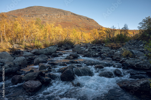 River flows in the vast landscape of Swedish Lapland on an autumn evening with surrounding autumn colors
